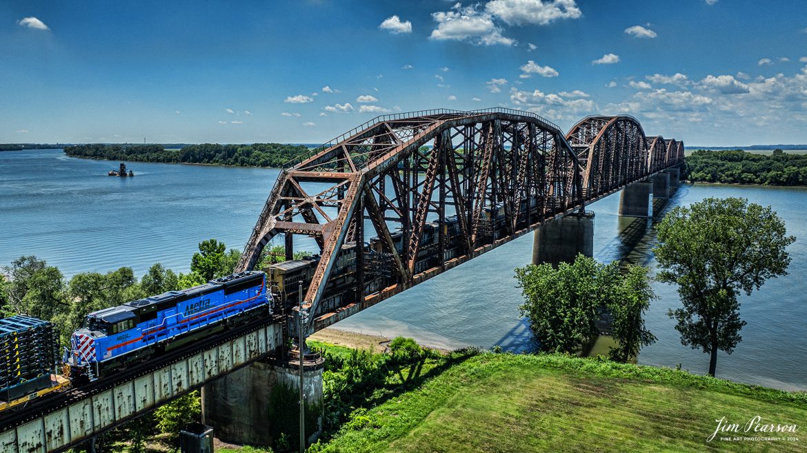 Metra 515 brings up the rear of six units leading CSX M512 as they head over the Ohio River Bridge at Henderson, Kentucky on their way north on June 27th, 2024, on the CSX Henderson Subdivision. Right behind the Metra unit is the start of a long string of Toyota Truck frames. 

I’m told that this is the first rebuilt ex-Kansas City unit by the Albertville, Ala.-based Progress Rail Services Corporation for Metra and part of an ongoing program and there are nine more being rebuilt numbered 515-523.

According to Wikipedia: Metra (reporting mark METX) is the primary commuter rail system in the Chicago metropolitan area serving the city of Chicago and its surrounding suburbs via the Union Pacific Railroad, BNSF Railway, and other railroads. The system operates 243 stations on 11 rail lines. It is the fourth busiest commuter rail system in the United States by ridership and the largest and busiest commuter rail system outside the New York City metropolitan area. In 2023, the system had a ridership of 31,894,900, or about 147,800 per weekday as of the first quarter of 2024. The estimated busiest day for Metra ridership occurred on November 4, 2016—the day of the Chicago Cubs 2016 World Series victory rally.

Metra is the descendant of numerous commuter rail services dating to the 1850s. The present system dates to 1974, when the Illinois General Assembly established the Regional Transportation Authority (RTA) to consolidate all public transit operations in the Chicago area, including commuter rail. The RTA's creation was a result of the anticipated failure of commuter service operated and owned by various private railroad companies in the 1970s. In a 1983 reorganization, the RTA placed commuter rail under a newly formed Commuter Rail Division, which branded itself as Metra in 1985. Freight rail companies still operate four of Metra's routes under purchase-of-service agreements. Metra owns all rolling stock and is responsible for all stations along with the respective municipalities. Since its inception, Metra has directed more than $5 billion into the commuter rail system of the Chicago metropolitan area alongside the CTA.

Tech Info: DJI Mavic 3 Classic Drone, RAW, 22mm, f/2.8, 1/2500, ISO 130.

#railroad #railroads #train #trains #bestphoto #railroadengines #picturesoftrains #picturesofrailway #bestphotograph #photographyoftrains #trainphotography #JimPearsonPhotography #trendingphoto #csxt #trainsfromadrone #metra