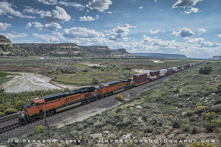 September 25, 2011 – BNSF 7567 and 7209 lead a long intermodal freight, elephant style, as they head east through Campbell Pass at the Continental Divide, New Mexico.

According to Wikipedia: Campbell Pass is an infrequently used name for a heavily travelled crossing of the Continental Divide in west-central New Mexico. This broad, gentle mountain pass, located in McKinley County between Gallup and Grants, is the site of the town of Continental Divide. 

The pass was selected as the route to be traversed by the original main line of the Atchison, Topeka and Santa Fe Railway in 1880 (now the Southern Transcon of the BNSF Railway). The famous U.S. Route 66 was built through the pass in 1926, and is now the route of its successor, Interstate 40.

The origin of the name Campbell Pass is obscure, and it appears to be used mostly in connection with the railroad.

Tech Info: Nikon D700, RAW, Nikon 18mm, f/9, 1/800, ISO 640.

#photographyoftrains #trainphotography #JimPearsonPhotography #trendingphoto #bnsf