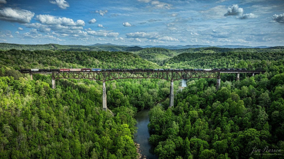 A trio of Norfolk Southern engines lead NS 168 as they make their way across the New River Bridge northbound on the NS CNO&TP (Rathole) Subdivision at New River, Tennessee. On April 29th, 2024.  

According to the Historic Bridges website: This bridge is a very large high level deck cantilever truss bridge. It was constructed in 1963 and as such is a late example of its type, but still noteworthy as an uncommon structure type and for its size. Typical of 1960s truss bridges, the bridge still has riveted built-up beams, but v-lacing and lattice are absent in the built-up beams, and truss connections are bolted instead of riveted. It is 1,622.0 Feet (494.4 Meters) long, with 3 Main Span(s) and 6 Approach Span(s) is over 300 feet above the river.

Tech Info: DJI Mavic 3 Classic Drone, RAW, 22mm, f/2.8, 1/2000, ISO 140.

#railroad #railroads #train #trains #bestphoto #railroadengines #picturesoftrains #picturesofrailway #bestphotograph #photographyoftrains #trainphotography #JimPearsonPhotography #nscnotpsubdivision #norfolksouthern #trendingphoto #nsnewriverbridge