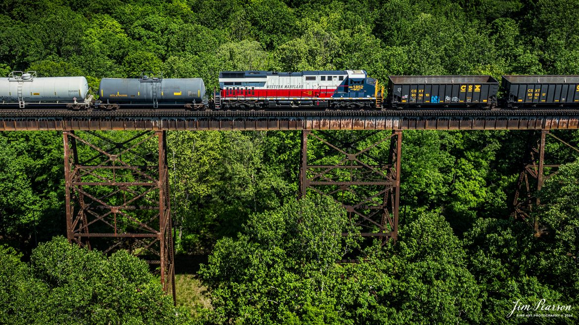 CSXT 1852, Western Maryland Heritage Unit, heads north as the mid-train DPU on X512 as it passes over Gum Lick Trestle, just north of Kelly, Kentucky on May 12th, 2024, northbound on the CSX Henderson Subdivision. 

This extra 512 actually had two heritage units as the Chesapeake & Ohio unit 1869 was the lead engine on this same train and I’ll be posting a shot of that engine at Sebree, Ky this afternoon! 

DPU Stands for Distributed Power Unit, a locomotive set capable of remote-control operation in conjunction with locomotive unites at the train's head end. DPUs are placed in the middle or at the rear of heavy trains (such as coal, or grain) to help climb steep grades.

From a CSX press release: April 9, 2024 - CSX has launched another addition to its locomotive fleet – the Western Maryland heritage locomotive. This new locomotive pays homage to the rich history of railroads in the Western Maryland region and symbolizes CSX's commitment to preserving and celebrating its railroad heritage.

The Western Maryland Railroad operated between 1852 and 1983 in Maryland, West Virginia, and Pennsylvania. It was a small railroad that primarily transported coal and freight. 

“In 1983 the Western Maryland fully merged with the B&O (Baltimore and Ohio Railroad), which merged with the C&O (Chesapeake and Ohio Railroad) in 1987. They eventually merged with the Seaboard System to form CSX.” explained Tim Music, a CSX carman painter who assisted with the project. 

The CSX Western Maryland heritage locomotive features a striking design inspired by the iconic colors and markings of the historic Western Maryland Railway. With its bold red, black, and gold livery, this locomotive stands out as a tribute to the legacy of railroading in the region.

“This was a smaller rail line but it is still an important part of our CSX history and we want to honor it,” shared Clyde Marshall, another CSX carman painter involved with the effort.

The Western Maryland is the twelfth heritage unit released by CSX in its current series, which underscores its appreciation for its railroad history as it continues to innovate for the future. The units are crafted at the company’s mechanical shop in Waycross, Georgia.

Tech Info: DJI Mavic 3 Classic Drone, RAW, 22mm, f/2.8, 1/1250, ISO 110.

#railroad #railroads #train #trains #bestphoto #railroadengines #picturesoftrains #picturesofrailway #bestphotograph #photographyoftrains #trainphotography #JimPearsonPhotography #trendingphoto #csxheritageunit