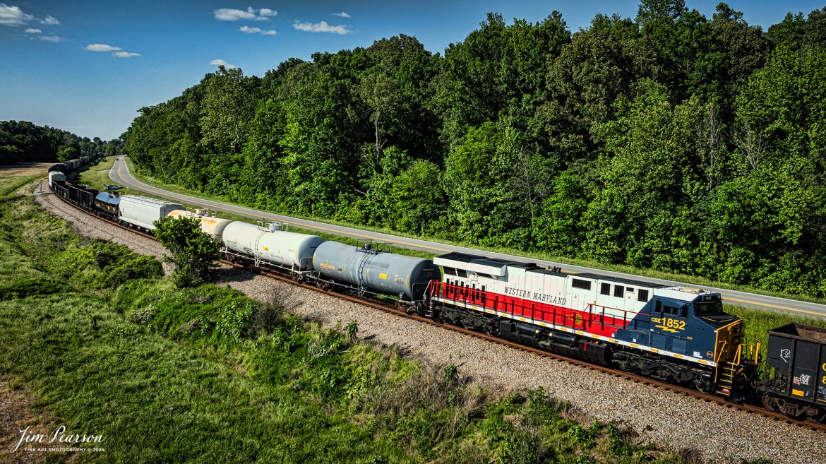 CSXT 1852, Western Maryland Heritage Unit, heads north as the mid-train DPU on X512 at Sebree, Kentucky on May 12th, 2024, northbound on the CSX Henderson Subdivision. This extra 512 actually had two heritage units as the Chesapeake & Ohio unit 1869 was the lead engine on this same train and I’ll be posting a shot of that engine crossing over Gum Lick Trestle this afternoon! 

DPU Stands for Distributed Power Unit, a locomotive set capable of remote-control operation in conjunction with locomotive unites at the train's head end. DPUs are placed in the middle or at the rear of heavy trains (such as coal, or grain) to help climb steep grades.

From a CSX press release: April 9, 2024 - CSX has launched another addition to its locomotive fleet – the Western Maryland heritage locomotive. This new locomotive pays homage to the rich history of railroads in the Western Maryland region and symbolizes CSX's commitment to preserving and celebrating its railroad heritage.

The Western Maryland Railroad operated between 1852 and 1983 in Maryland, West Virginia, and Pennsylvania. It was a small railroad that primarily transported coal and freight. 

“In 1983 the Western Maryland fully merged with the B&O (Baltimore and Ohio Railroad), which merged with the C&O (Chesapeake and Ohio Railroad) in 1987. They eventually merged with the Seaboard System to form CSX.” explained Tim Music, a CSX carman painter who assisted with the project. 

The CSX Western Maryland heritage locomotive features a striking design inspired by the iconic colors and markings of the historic Western Maryland Railway. With its bold red, black, and gold livery, this locomotive stands out as a tribute to the legacy of railroading in the region.

“This was a smaller rail line but it is still an important part of our CSX history and we want to honor it,” shared Clyde Marshall, another CSX carman painter involved with the effort.

The Western Maryland is the twelfth heritage unit released by CSX in its current series, which underscores its appreciation for its railroad history as it continues to innovate for the future. The units are crafted at the company’s mechanical shop in Waycross, Georgia.

Tech Info: DJI Mavic 3 Classic Drone, RAW, 22mm, f/2.8, 1/2000, ISO 160.

#railroad #railroads #train #trains #bestphoto #railroadengines #picturesoftrains #picturesofrailway #bestphotograph #photographyoftrains #trainphotography #JimPearsonPhotography #trendingphoto #csxheritageunit