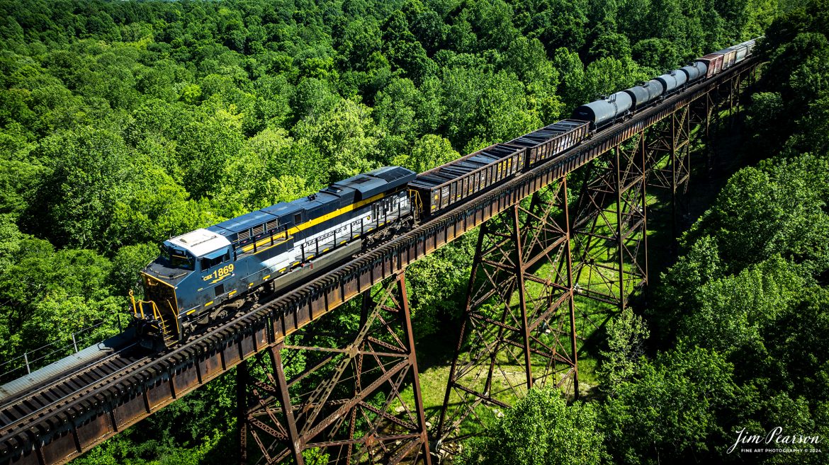 CSXT 1869, Chesapeake & Ohio, heads north as the lead engine on X512 as it crosses Gum Lick Trestle, north of Kelly, Kentucky on May 12th, 2024, on the CSX Henderson Subdivision. 

From a CSX Press Release: A locomotive commemorating the proud history of the Chesapeake and Ohio Railway has entered service as the fifth in the CSX heritage series celebrating the lines that came together to form the modern railroad.
 
Numbered CSX 1869 in honor of the year the C&O was formed in Virginia from several smaller railroads, the newest heritage locomotive sports a custom paint design that includes today’s CSX colors on the front of the engine and transitions to a paint scheme inspired by 1960s era C&O locomotives on the rear two-thirds.

The C&O Railway was a major line among North American freight and passenger railroads for nearly a century before becoming part of the Chessie System in 1972 and eventually merging into the modern CSX. In 1970, the C&O included more than 5,000 route miles of track stretching from Newport News, Virginia, to Chicago and the Great Lakes. 

Tech Info: DJI Mavic 3 Classic Drone, RAW, 22mm, f/2.8, 1/640, ISO 100.

#railroad #railroads #train #trains #bestphoto #railroadengines #picturesoftrains #picturesofrailway #bestphotograph #photographyoftrains #trainphotography #JimPearsonPhotography #trendingphoto #csxheritageunit