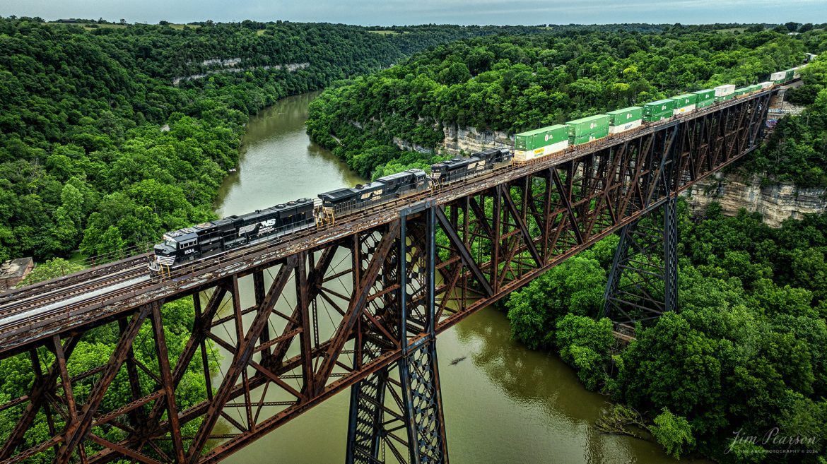 Norfolk Southern intermodal 29F heads southbound across High Bridge on June 8th, 2024, crossing the Kentucky River on the NS CNO&TP First District at Highbridge, Kentucky.

According to Wikipedia: The High Bridge is a railroad bridge crossing the Kentucky River Palisades, that rises approximately 275 feet from the river below and connects Jessamine and Mercer counties in Kentucky. Formally dedicated in 1879, it is the first cantilever bridge constructed in the United States. It has a three-span continuous under-deck truss used by Norfolk Southern Railway to carry trains between Lexington and Danville. It has been designated as a National Historic Civil Engineering Landmark.

In 1851, the Lexington & Danville Railroad, with Julius Adams as chief engineer, retained John A. Roebling to build a railroad suspension bridge across the Kentucky River for a line connecting Lexington and Danville, Kentucky west of the intersection of the Dix and Kentucky rivers. In 1855, the company ran out of money and the project was resumed by Cincinnati Southern Railroad in 1873 following a proposal by C. Shaler Smith for a cantilever design using stone towers designed by John A. Roebling (who designed the Brooklyn Bridge).

The bridge was erected using a cantilever design with a three-span continuous under-deck truss and was opened in 1877 on the Cincinnati Southern Railway. It was 275 feet (84 m) tall and 1,125 feet (343 m) long: the tallest bridge above a navigable waterway in North America and the tallest railroad bridge in the world until the early 20th century. Construction was completed using 3,654,280 pounds of iron at a total cost of $404,373.31. In 1879 President Rutherford B. Hayes and Gen. William Tecumseh Sherman attended the dedication.

After years of heavy railroad use, the bridge was rebuilt by Gustav Lindenthal in 1911. Lindenthal reinforced the foundations and rebuilt the bridge around the original structure. To keep railroad traffic flowing, the track deck was raised by 30 feet during construction and a temporary trestle was constructed. In 1929, an additional set of tracks was built to accommodate increased railroad traffic and the original limestone towers were removed.

Tech Info: DJI Mavic 3 Classic Drone, RAW, 24mm, f/2.8, 1/640, ISO 180.

#trainphotography #railroadphotography #trains #railways #trainphotographer #railroadphotographer #jimpearsonphotography #NorfolkSouthern #KentuckyTrains