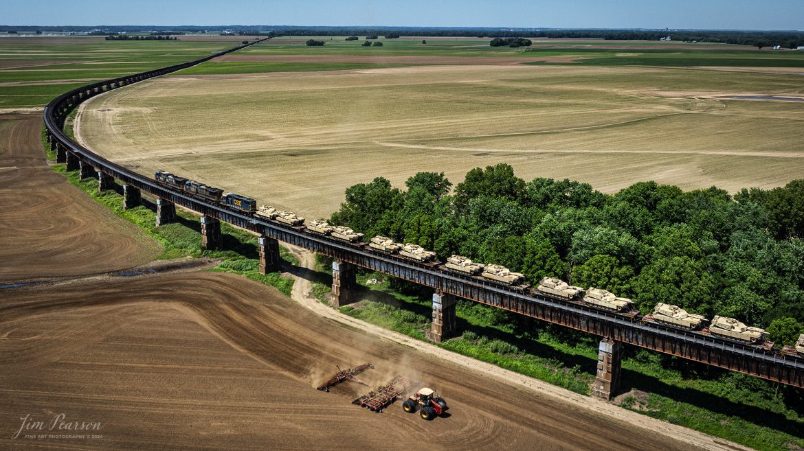 A farmer works on preparing his fields as CSX M512 heads north on the viaduct at Rahm, Indiana, on June 13th, 2024, with a string of 30 M1 Tanks in their consist as they head north on the CSX Henderson Subdivision. The viaduct here travels over a flood plain on the Ohio River.

Tech Info: DJI Mavic 3 Classic Drone, RAW, 22mm, f/2.8, 1/2000, ISO 130.

#railroad #railroads #train #trains #bestphoto #railroadengines #picturesoftrains #picturesofrailway #bestphotograph #photographyoftrains #trainphotography #JimPearsonPhotography #trendingphoto #csxt #trainsfromadrone #military