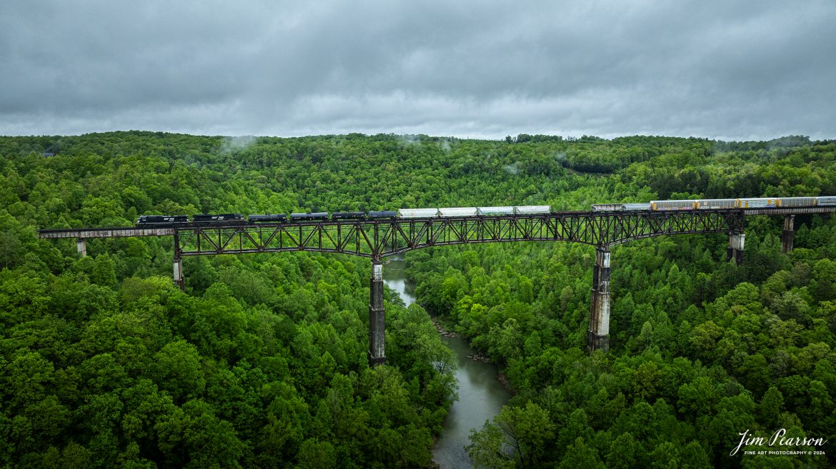 Norfolk Southern 167 makes their way across the New River Bridge under stormy skies as they head southbound on the NS CNO&TP (Rathole) Second District at New River, Tennessee. On April 30th, 2024.  

According to the Historic Bridges website: This bridge is a very large high level deck cantilever truss bridge. It was constructed in 1963 and as such is a late example of its type, but still noteworthy as an uncommon structure type and for its size. Typical of 1960s truss bridges, the bridge still has riveted built-up beams, but v-lacing and lattice are absent in the built-up beams, and truss connections are bolted instead of riveted. It is 1,622.0 Feet (494.4 Meters) long, with 3 Main Span(s) and 6 Approach Span(s) is over 300 feet above the river.

Tech Info: DJI Mavic 3 Classic Drone, RAW, 22mm, f/2.8, 1/400, ISO 140.

#railroad #railroads #train #trains #bestphoto #railroadengines #picturesoftrains #picturesofrailway #bestphotograph #photographyoftrains #trainphotography #JimPearsonPhotography #nscnotpsubdivision #norfolksouthern #trendingphoto #nsnewriverbridge