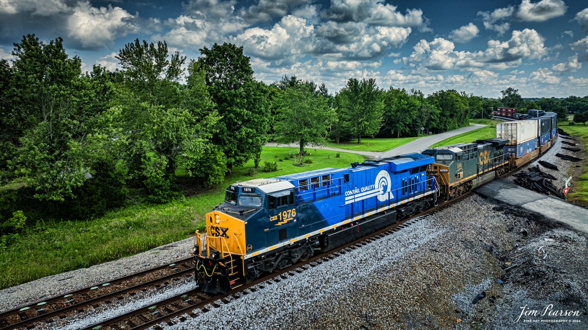 The CSX Conrail Heritage Locomotive leads CSX I026 northbound at the north end of Kelly, Ky, on July 10th, 2024, on the CSX Henderson Subdivision as they make their daily run to Chicago, Illinois.

According to a CSX Press Release: July 22, 2023 – CSX has unveiled the fourth locomotive in its series of custom paint designs that honor its heritage railroads. The latest in the series commemorates the Consolidated Rail Corporation, or Conrail, and bears the number 1976, the year the railroad was founded.

CSX and Norfolk Southern acquired and divided most of the Conrail network in 1997. Today, the company continues to exist as a terminal and switching railroad for CSX and NS customers in North Jersey-New York City metro area.

The Conrail paint scheme of a double-lined C inside a large, bold Q was a fixture for many years across the Northeast where the majority of the railroad’s operations were centered. The heritage locomotive design conceived and executed at CSX’s locomotive shop in Waycross, Georgia, recreates the iconic “Conrail Quality” logo and features Conrail blue on the rear two-thirds of the engine, then transitions to the current CSX colors and design on the cab portion of the unit.

CSX 1976 and other locomotives in the heritage series will be placed into revenue service and travel CSX’s 20,000 rail network, reinforcing employee pride in the history of the railroad that continues to move the nation’s economy with safe, reliable and sustainable rail-based transportation services.

Tech Info: DJI Mavic 3 Classic Drone, RAW, 22mm, f/2.8, 1/2000, ISO 220.

#railroad #railroads #train #trains #bestphoto #railroadengines #picturesoftrains #picturesofrailway #bestphotograph #photographyoftrains #trainphotography #JimPearsonPhotography #trendingphoto