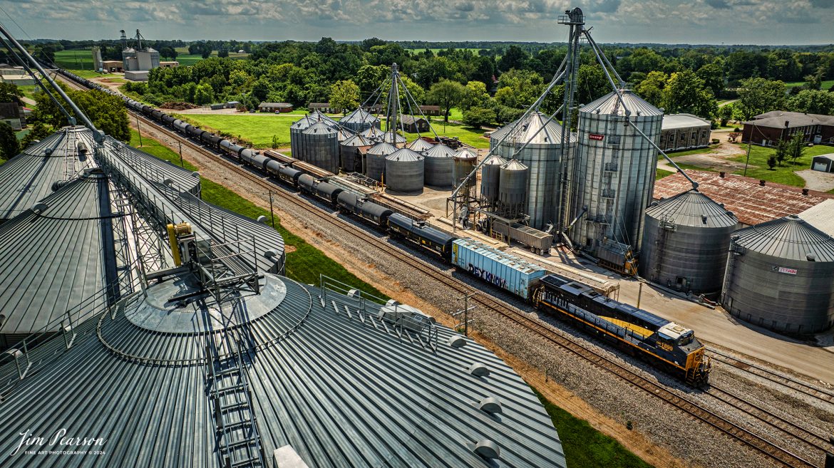 CSX empty ethanol train B722 heads northbound with CSX Pere Marquette Heritage Unit 1899 leading the way on the CSX Henderson Subdivision, as they pass the between the WF Ware grain complex at Trenton, Kentucky, on July 31st, 2024.

According to a CSX Press Release: May 1, 2024 – CSX has introduced the latest addition in its heritage locomotive series, paying homage to the rich history of the Pere Marquette Railroad. This new unit showcases the Pere Marquette’s legacy, dating back to its inception on November 1, 1899.

The Pere Marquette Railroad, operating in the Great Lakes region of the United States and parts of southern Ontario, Canada, derived its name from Jacques Marquette, a notable French Jesuit missionary credited with founding Michigan’s first European settlement in Sault Ste Marie. After years of operation, the company merged with the Chesapeake and Ohio Railway (C&O) on June 6, 1947, eventually becoming part of the renowned CSX network.

The design of the Pere Marquette heritage locomotive was meticulously crafted by employees at the CSX Waycross Locomotive Shop. According to CSX Carman Painter Eric Lee, “We had to measure each stripe precisely and position the words just right to ensure it captured the look of the original design. It took us about four days just to lay out the stripes before we could begin painting.”

A fascinating tidbit related to the history of Pere Marquette is its cameo in the 2004 film “The Polar Express.” The steam locomotive Pere Marquette 1225 served as the inspiration for the train depicted in the movie, with audio recordings of the actual locomotive in operation featured in the film. Interestingly, the locomotive had been donated to Michigan State University and was exhibited near the university’s football stadium. The author of “The Polar Express” book drew inspiration from seeing this locomotive on display during childhood, solidifying its place in popular culture.

CSX’s dedication to honoring the history and significance of the Pere Marquette Railroad through this new locomotive underscores the company’s commitment to preserving and celebrating the heritage of American railroads. Keep an eye out as this remarkable piece of history moves across the CSX network, bridging the past with the present.

Tech Info: DJI Mavic 3 Classic Drone, RAW, 22mm, f/2.8, 1/2500, ISO 100.

#railroad #railroads #train #trains #bestphoto #railroadengines #picturesoftrains #picturesofrailway #bestphotograph #photographyoftrains #trainphotography #JimPearsonPhotography #trendingphoto #csxt #trainsfromadrone #csxheritage