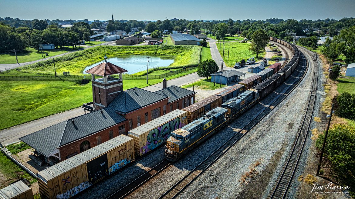 CSXT 5313 leads CSX loaded coal train C040 as it passes the old L&N Railway depot at Henderson, Kentucky on their way south on the Henderson Subdivision on March August 6th, 2024.

Railmark Holdings, Inc purchased the depot and is currently continuing restoration on the station. I’ve still not been able to find out what their plans for the depot include yet.

According to their website: Railmark, its brands, and subsidiaries are leaders in the railroad industry in North America and around the world. An accomplished provider of railroad transportation, rail services, and rail systems development, Railmark provides a complete and fully integrated program for rail network improvement and rail management services to railroads, governments, municipalities, and industrial clients.

Railmark also owns and operates railroads in North America and sponsors philanthropic initiatives through its Railmark Foundation Limited. Together the Railmark group of rail service companies work around the world each day to make rail transportation better by improving economies and the quality of human life.

Tech Info: DJI Mavic 3 Classic Drone, RAW, 22mm, f/2.8, 1/4000, ISO 210.

#railroad #railroads #train #trains #bestphoto #railroadengines #picturesoftrains #picturesofrailway #bestphotograph #photographyoftrains #trainphotography #JimPearsonPhotography #trendingphoto #csxt #trainsfromadrone