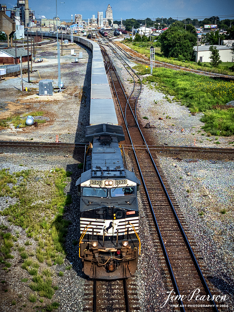 Norfolk Southern 9839 leads Triple Crown RoadRailer train NS 255 westbound as it passes over the WABAC Diamond as they depart from Decatur, Illinois after a crew change on August 24th, 2024, as they head west on the NS Lafayette District. 

The NS RoadRailer trains are now a thing of the past as the last one ran yesterday, 25th of August 2024, and the service has now been discontinued and they will transition fully to standard double-stack trains.

According to Wikipedia: A RoadRailer is a trailer or semi-trailer that can be hauled on roads by a tractor unit and then by way of a fifth wheel coupling, operate in a unit train on railway lines. The RoadRailer system allows trailers to be pulled by locomotives without the use of flatcars, instead attaching trailers directly to bogies.

Triple Crown, a subsidiary of Norfolk Southern Railway, remains a user of RoadRailer transportation as of 2022. However, on August 12th, 2024, they announced the last RoadRailer Trains would be running the weekend of August 24 and 25, 2024. The RoadRailer trains will be replaced temporarily with Trailer on Flat Car (TOFC) service before transitioning fully to a standard double-stack container trains.

Tech Info: DJI Mavic 3 Classic Drone, RAW, 22mm, f/2.8, 1/2000, ISO 100.

#trainphotography #railroadphotography #trains #railways #trainphotographer #railroadphotographer #jimpearsonphotography #NorfolkSouthern #IllinoisRailroads