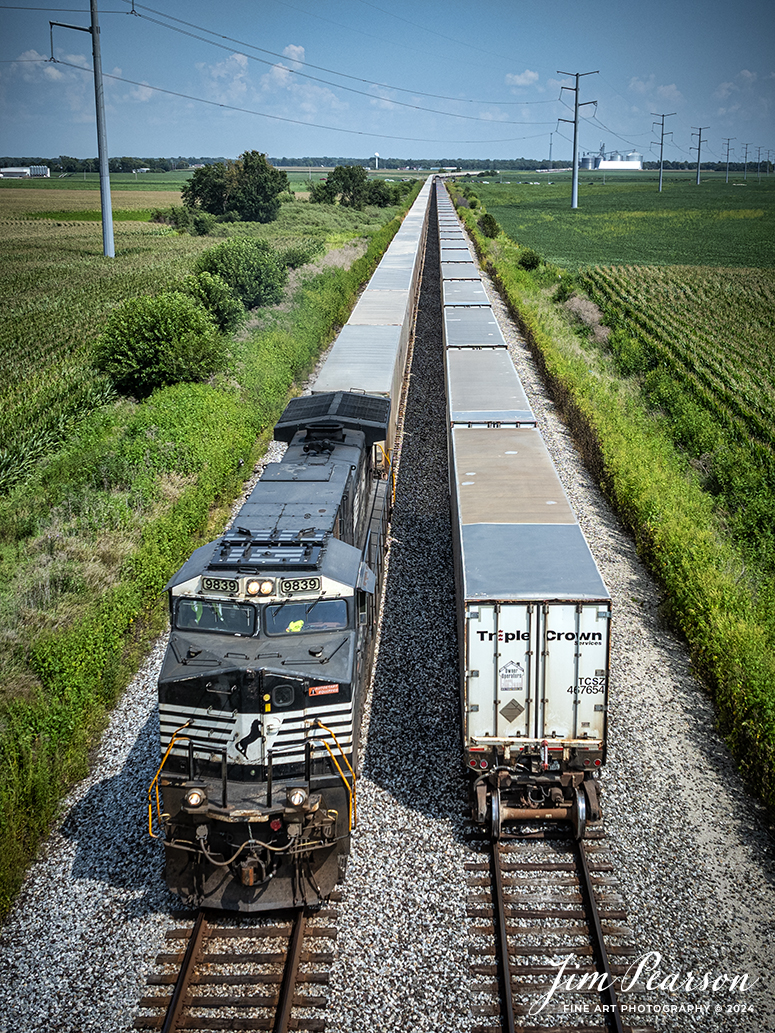 Norfolk Southern 9839 leads Triple Crown RoadRailer NS 255  as it passes the tail end of it's counterpart, NS 256 at Sidney, Illinois on the NS Lafayette District on August 24th, 2024. 

This is the end of an era for this scene with RoadRailers as both trains are being changed over to Intermodals and today was the last run for eastbound 256 and the 25th was the last run for NS 255. 


According to Wikipedia: A RoadRailer is a trailer or semi-trailer that can be hauled on roads by a tractor unit and then by way of a fifth wheel coupling, operate in a unit train on railway lines. The RoadRailer system allows trailers to be pulled by locomotives without the use of flatcars, instead attaching trailers directly to bogies.

Triple Crown, a subsidiary of Norfolk Southern Railway, remains a user of RoadRailer transportation as of 2022. However, on August 12th, 2024, they announced the last RoadRailer Trains would be running the weekend of August 24 and 25, 2024. The RoadRailer trains will be replaced temporarily with Trailer on Flat Car (TOFC) service before transitioning fully to a standard double-stack container trains.

Tech Info: DJI Mavic 3 Classic Drone, RAW, 22mm, f/2.8, 1/2000, ISO 100.

#trainphotography #railroadphotography #trains #railways #trainphotographer #railroadphotographer #jimpearsonphotography #NorfolkSouthern #IllinoisRailroads