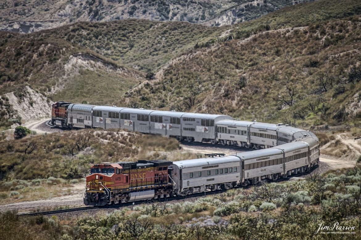 June 6, 2006 - BNSF 4419 leads a business train east bound through the Cajon Pass in southern California, headed to Barstow, CA.

According to Wikipedia: Cajon Pass is a mountain pass between the San Bernardino Mountains to the east and the San Gabriel Mountains to the west in Southern California. Created by the movements of the San Andreas Fault, it has an elevation of 3,777 ft (1,151 m). Located in the Mojave Desert, the pass is an important link from the Greater San Bernardino Area to the Victor Valley, and northeast to Las Vegas. The Cajon Pass area is on the Pacific Crest Trail.

Cajon Pass is at the head of Horsethief Canyon, traversed by California State Route 138 (SR 138) and railroad tracks owned by BNSF Railway and Union Pacific Railroad. Improvements in 1972 reduced the railroad's maximum elevation from about 3,829 to 3,777 feet while reducing curvature. Interstate 15 does not traverse Cajon Pass, but rather the nearby Cajon Summit. The entire area, Cajon Pass and Cajon Summit, is often referred to as Cajon Pass, but a distinction is made between Cajon Pass and Cajon Summit.

The California Southern Railroad, a subsidiary of the Atchison, Topeka and Santa Fe Railway, was the first railroad through Cajon Pass. The line through the pass was built in the early 1880s to connect the present-day cities of Barstow and San Diego. Today the Union Pacific Railroad and BNSF Railway (the successor to the Santa Fe) use the pass to reach Los Angeles and San Bernardino as part of the Southern Transcon. Due to the many trains, scenery and easy access, it is a popular location for railfans, and many photographs of trains on Cajon Pass appear in books and magazines.

Tech Info: Nikon D200, RAW, Nikon 70-300 @ 200mm, f/6.3, 1/400, ISO 100.

#railroad #railroads #train, #trains #railway #railway #steamtrains #railtransport #railroadengines #picturesoftrains #picturesofrailways #besttrainphotograph #bestphoto #photographyoftrains #bestsoldpicture #JimPearsonPhotography #trainsfromtheair #CajonPass #bnsf