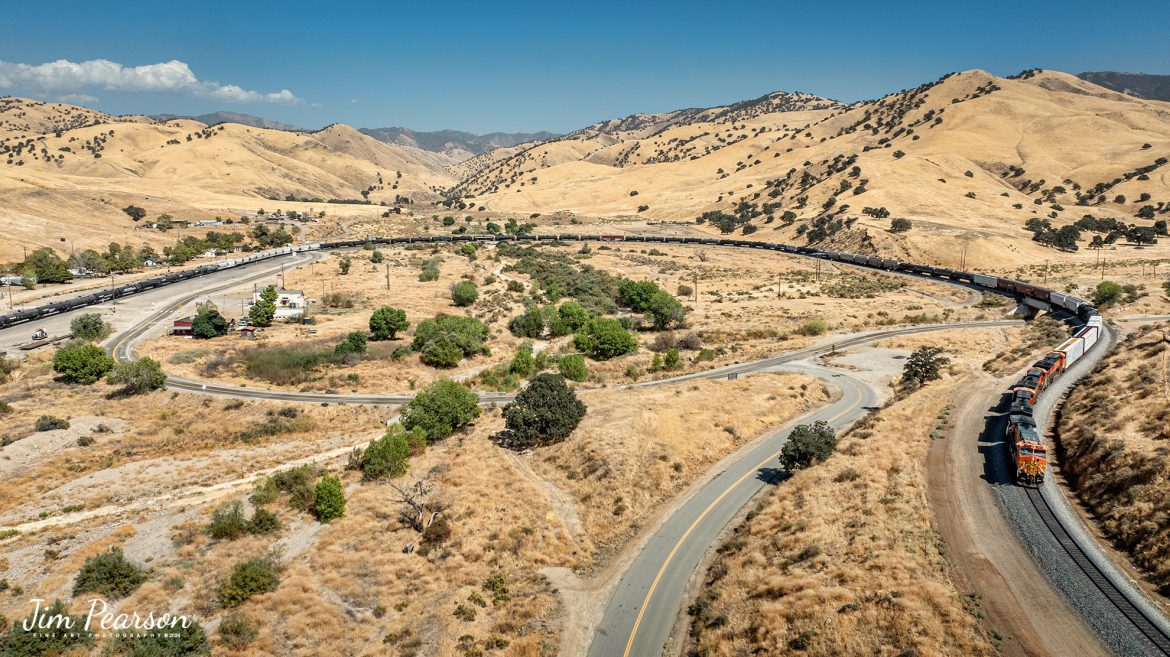 September 18th, 2024, A BNSF eastbound train works its way through the horseshoe curve on the Union Pacific Mojave Subdivision at Caliente, California, starting their climb through the Tehachapi Pass.

According to Wikipedia: Established in the 1870s, Caliente was originally named Allens Camp for a cattle rancher and settler named Gabriel Allen. Later, the name Agua Caliente, coming from hot springs in the area, was proposed and may have been used. This name conflicted with the community of the same name in Sonoma County. With the railroad's arrival in 1875, the shortened name Caliente was adopted.

Caliente prospered during Southern Pacific Railroad's construction of Tehachapi Pass line. For a time, the Telegraph Stage Line and the Cerro Gordo Freighting Co. also ran through Caliente and its full-time population grew to 200. There were approximately 60 buildings, including 20 or more saloons.

Tech Info: DJI Mavic 3 Classic Drone, RAW, 24mm, f/2.8, 1/3200, ISO 100.

#railroad #railroads #train, #trains #railway #railway #steamtrains #railtransport #railroadengines #picturesoftrains #picturesofrailways #besttrainphotograph #bestphoto #photographyoftrains #bestsoldpicture #JimPearsonPhotography #trainsfromtheair #trainsfromadrone