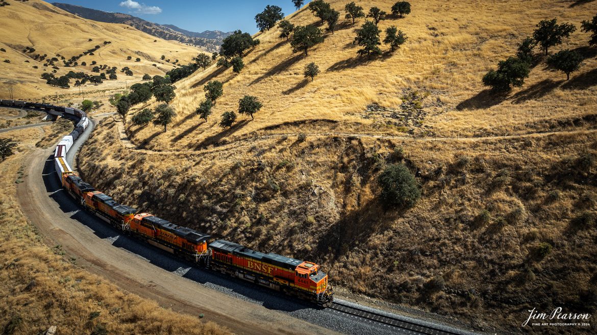 September 18th, 2024, A BNSF northbound train works its way out of the horseshoe curve on the Union Pacific Mojave Subdivision at Caliente, California, starting their climb up through the Tehachapi Pass.

According to Wikipedia: Established in the 1870s, Caliente was originally named Allens Camp for a cattle rancher and settler named Gabriel Allen. Later, the name Agua Caliente, coming from hot springs in the area, was proposed and may have been used. This name conflicted with the community of the same name in Sonoma County. With the railroad's arrival in 1875, the shortened name Caliente was adopted.

Caliente prospered during Southern Pacific Railroad's construction of Tehachapi Pass line. For a time, the Telegraph Stage Line and the Cerro Gordo Freighting Co. also ran through Caliente and its full-time population grew to 200. There were approximately 60 buildings, including 20 or more saloons.

Tech Info: DJI Mavic 3 Classic Drone, RAW, 24mm, f/2.8, 1/1600, ISO 100.

#railroad #railroads #train, #trains #railway #railway #steamtrains #railtransport #railroadengines #picturesoftrains #picturesofrailways #besttrainphotograph #bestphoto #photographyoftrains #bestsoldpicture #JimPearsonPhotography #trainsfromtheair #trainsfromadrone