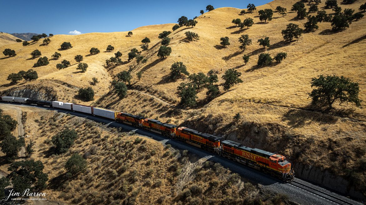 September 18th, 2024, A BNSF northbound train works its way out of the horseshoe curve on the Union Pacific Mojave Subdivision at Caliente, California, starting their climb up through the Tehachapi Pass.

According to Wikipedia: Established in the 1870s, Caliente was originally named Allens Camp for a cattle rancher and settler named Gabriel Allen. Later, the name Agua Caliente, coming from hot springs in the area, was proposed and may have been used. This name conflicted with the community of the same name in Sonoma County. With the railroad's arrival in 1875, the shortened name Caliente was adopted.

Caliente prospered during Southern Pacific Railroad's construction of Tehachapi Pass line. For a time, the Telegraph Stage Line and the Cerro Gordo Freighting Co. also ran through Caliente and its full-time population grew to 200. There were approximately 60 buildings, including 20 or more saloons.

Tech Info: DJI Mavic 3 Classic Drone, RAW, 24mm, f/2.8, 1/1600, ISO 100.

#railroad #railroads #train, #trains #railway #railway #steamtrains #railtransport #railroadengines #picturesoftrains #picturesofrailways #besttrainphotograph #bestphoto #photographyoftrains #bestsoldpicture #JimPearsonPhotography #trainsfromtheair #trainsfromadrone