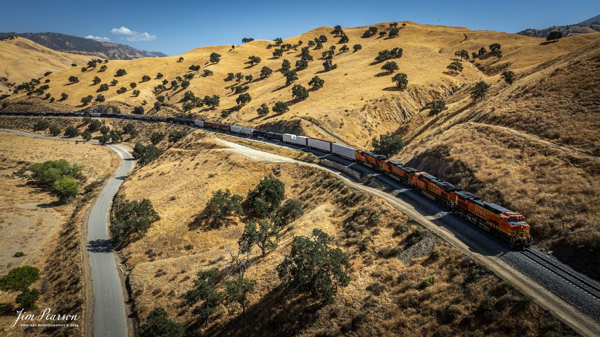 September 18th, 2024, A BNSF northbound train works its way out of the horseshoe curve on the Union Pacific Mojave Subdivision at Caliente, California, starting their climb up through the Tehachapi Pass.

According to Wikipedia: Established in the 1870s, Caliente was originally named Allens Camp for a cattle rancher and settler named Gabriel Allen. Later, the name Agua Caliente, coming from hot springs in the area, was proposed and may have been used. This name conflicted with the community of the same name in Sonoma County. With the railroad's arrival in 1875, the shortened name Caliente was adopted.

Caliente prospered during Southern Pacific Railroad's construction of Tehachapi Pass line. For a time, the Telegraph Stage Line and the Cerro Gordo Freighting Co. also ran through Caliente and its full-time population grew to 200. There were approximately 60 buildings, including 20 or more saloons.

Tech Info: DJI Mavic 3 Classic Drone, RAW, 24mm, f/2.8, 1/1600, ISO 100.

#railroad #railroads #train, #trains #railway #railway #steamtrains #railtransport #railroadengines #picturesoftrains #picturesofrailways #besttrainphotograph #bestphoto #photographyoftrains #bestsoldpicture #JimPearsonPhotography #trainsfromtheair #trainsfromadrone