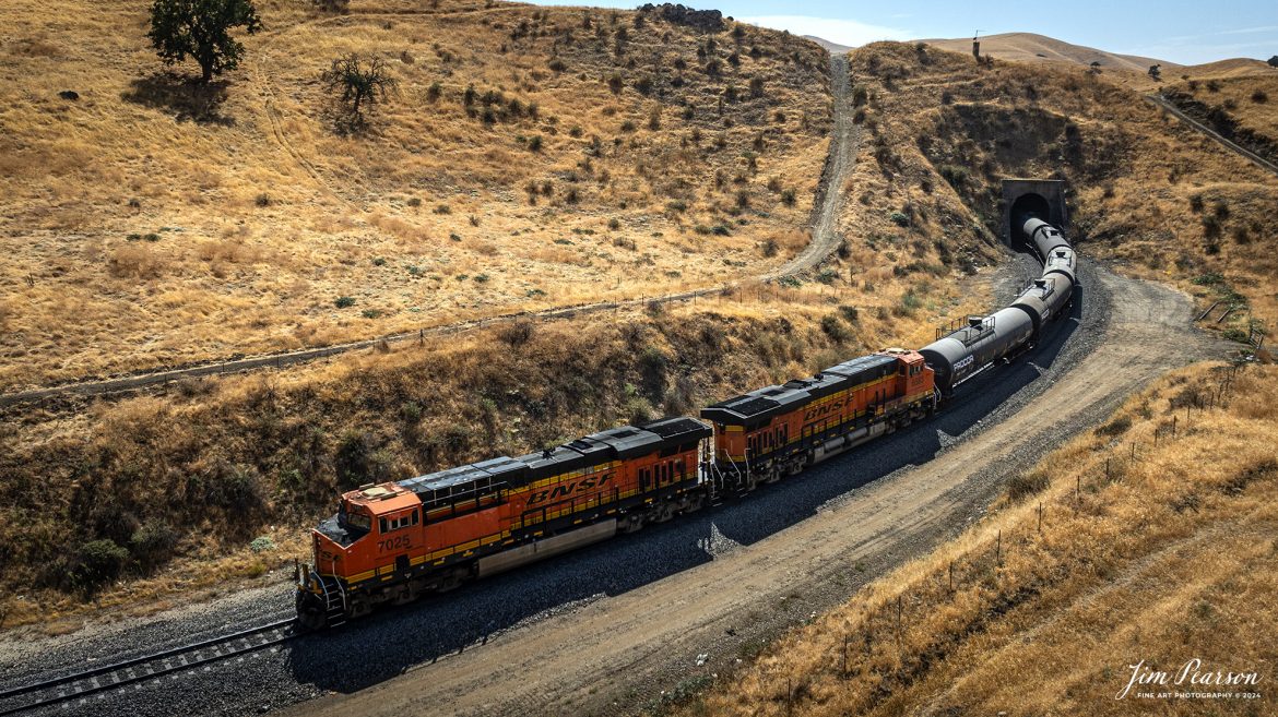 September 18th, 2024, The DPU end of a BNSF northbound train prepares to pass through one of the many tunnels on the Union Pacific Mojave Subdivision at Caliente, California, during their climb up through the Tehachapi Pass.

According to Wikipedia: Established in the 1870s, Caliente was originally named Allens Camp for a cattle rancher and settler named Gabriel Allen. Later, the name Agua Caliente, coming from hot springs in the area, was proposed and may have been used. This name conflicted with the community of the same name in Sonoma County. With the railroad's arrival in 1875, the shortened name Caliente was adopted.

Caliente prospered during Southern Pacific Railroad's construction of Tehachapi Pass line. For a time, the Telegraph Stage Line and the Cerro Gordo Freighting Co. also ran through Caliente and its full-time population grew to 200. There were approximately 60 buildings, including 20 or more saloons.

Tech Info: DJI Mavic 3 Classic Drone, RAW, 24mm, f/2.8, 1/3200, ISO 150.

#railroad #railroads #train, #trains #railway #railway #steamtrains #railtransport #railroadengines #picturesoftrains #picturesofrailways #besttrainphotograph #bestphoto #photographyoftrains #bestsoldpicture #JimPearsonPhotography #trainsfromtheair #trainsfromadrone