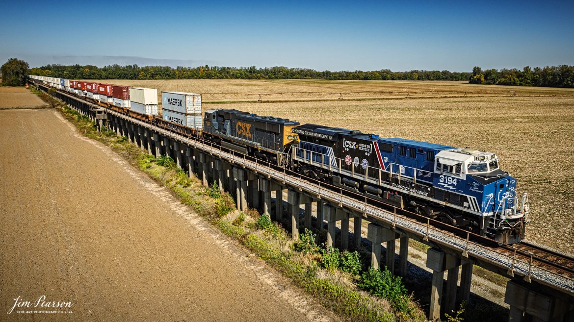 CSX I025 sits at the beginning of the viaduct that passes over the flood plain leading up to the bridge at Henderson, Ky that crosses over the Ohio River with the CSXT Pride in Service Honoring Our Law Enforcement unit leading on October 26th, 2024. 

The train was held up for about 2 hours as members of the Henderson Fire Department finished putting out a tie fire on the bridge that spans the river on the CSX Henderson Subdivision at Henderson, Kentucky; fortunately, except for the ties, the bridge is made out of steel.

CSXT 3194 is painted primarily in black, blue and white, with the slogans “To Protect and Serve” and “Honoring Our Law Enforcement.” It also prominently features the CSX Transportation Railroad Police logo, as well as police, fire and emergency responder logos.

Tech Info: DJI Mavic 3 Classic Drone, RAW, 24mm, f/5, 1/2500, ISO 100.

#picturesofrailways #besttrainphotograph #bestphoto #photographyoftrains #bestsoldpicture #JimPearsonPhotography