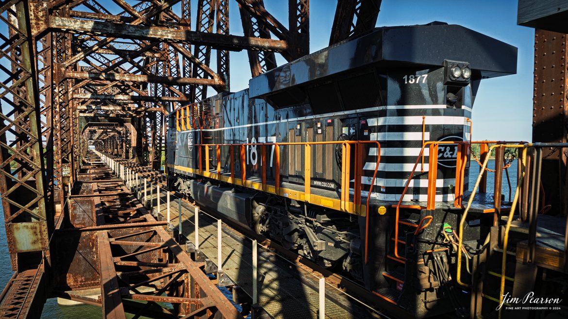 CSX M648 with the Chicago and Eastern Illinois Railroad (CE&I) heritage unit leading heads north across the Ohio River from Henderson, Kentucky, after members of the Henderson Fire Department finished putting out an initial tie fire on the bridge that spans the river on the CSX Henderson Subdivision at Henderson, Kentucky on October 26th, 2024, and fortunately except for the ties, the bridge is made out of steel.

The fire did disrupt traffic on the CSX Henderson Subdivision for a couple hours and while CSX M648 did make it across after being delayed about 30 minutes and after the ties were first put out, afterwards the ties reignited and delayed hot intermodal I025 on the Evansville, IN, side of the river for almost two hours, till the ties were completely extinguished. 

According to the CSX Website: July 26, 2024 - CSX has unveiled its 17th heritage locomotive, paying tribute to the historic Chicago and Eastern Illinois Railroad. This locomotive is part of CSX's ongoing series celebrating the rich legacy of America's railroads.

The C&EI was established in 1877, initially serving as a regional line connecting Chicago with southern Illinois, St. Louis, Mo. and Evansville, Ind. Over time, it expanded its reach, becoming an important link between the Midwest and the southern United States. The C&EI played a vital role in transporting coal, agricultural products, and manufactured goods, significantly contributing to the region's economic development.

In 1967, the C&EI was absorbed by the Missouri Pacific Railroad and the Louisville and Nashville Railroad. In the 1980s, as CSX expanded its network, it acquired various lines and assets from other railroads, including parts of former C&EI lines that had been integrated into the Missouri Pacific. This indirect acquisition process allowed CSX to incorporate the historic routes and legacy of the C&EI into its expansive system.

Tech Info: DJI Mavic 3 Classic Drone, RAW, 24mm, f/5, 1/1250, ISO 210.

#picturesofrailways #besttrainphotograph #bestphoto #photographyoftrains #bestsoldpicture #JimPearsonPhotography