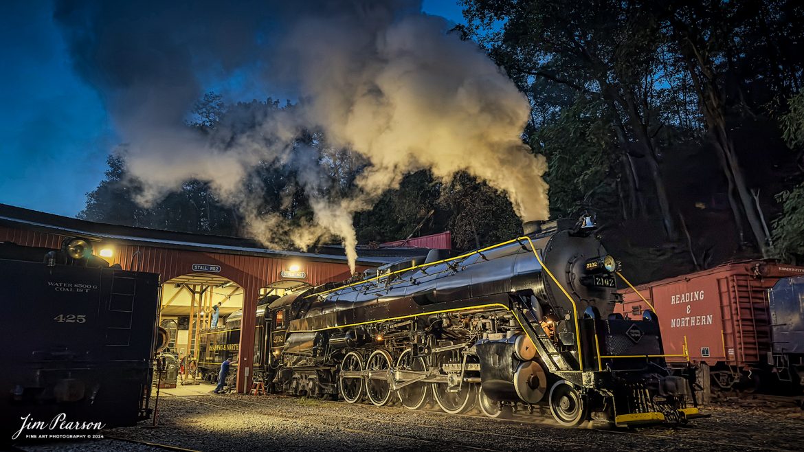 Reading Blue Mountain & Northern Railroad steam locomotive 2102 sits outside the engine house as dawn begins at Port Clinton, Pennsylvania on October 5th, 2024, as it waits to begin its first day of the year of pulling Fall Foliage Excursions.

According to their website: The Reading Company T-1 class #2102 was built in the Reading’s own locomotive shops in 1945. With drivers of 70” diameter, it weighs 404 tons, and its tender holds up to 26 tons of coal, and up to 19,000 gallons of water. After the Reading Steam era was over, the Reading Company used 2102 for the Reading Rambles on several different excursions. The 2102 has had many different owners since it was retired by the Reading Railroad. It is one of only four to survive. The other remaining locomotives are the 2100, 2101, and 2124.

The Blue Mountain and Reading Railroad purchased the 2102 in 1987, and it ran on the Temple to South Hamburg line into the early 1990’s. Once the Blue Mountain and Reading Railroad became the Reading Blue Mountain & Northern, the 2102 ran over Reading & Northern’s rails for a short time before it was removed from service in the early 1990’s. 

In 2022, steam locomotive 2102 reentered service on the Reading & Northern. The locomotive has been used actively to pull both passenger excursions and revenue freight trains.

Tech Info: iPhone 14 Pro, normal lens, f/1.8, 1/30th, ISO 800.

#railroad #railroads #train, #trains #railway #railway #steamtrains #railtransport #railroadengines #picturesoftrains #picturesofrailways #besttrainphotograph #bestphoto #photographyoftrains #bestsoldpicture #JimPearsonPhotography #RBNRR #iPhone