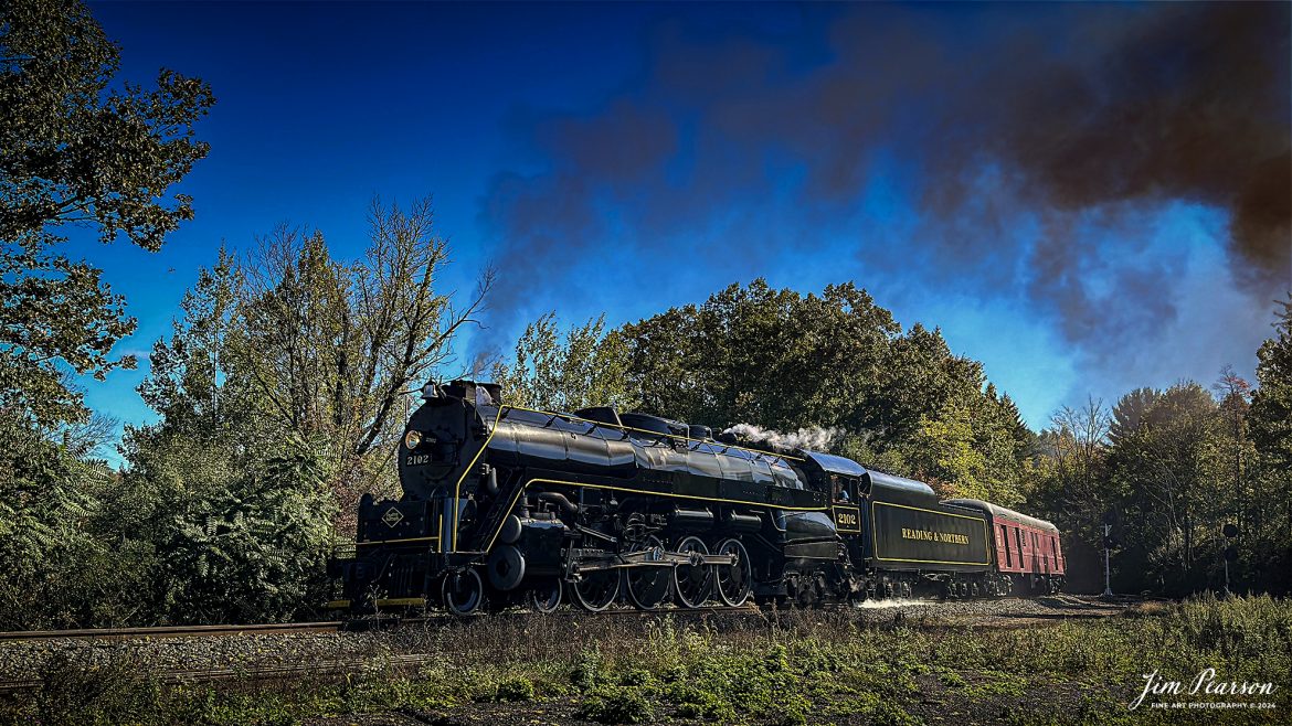 Reading Blue Mountain & Northern Railroad steam locomotive 2102 heads to Jim Thorp, Pennsylvania on October 5th, 2024, from Port Clinton, PA during their first day of the year of pulling Fall Foliage Excursions.

According to their website: The Reading Company T-1 class #2102 was built in the Reading’s own locomotive shops in 1945. With drivers of 70” diameter, it weighs 404 tons, and its tender holds up to 26 tons of coal, and up to 19,000 gallons of water. After the Reading Steam era was over, the Reading Company used 2102 for the Reading Rambles on several different excursions. The 2102 has had many different owners since it was retired by the Reading Railroad. It is one of only four to survive. The other remaining locomotives are the 2100, 2101, and 2124.

The Blue Mountain and Reading Railroad purchased the 2102 in 1987, and it ran on the Temple to South Hamburg line into the early 1990’s. Once the Blue Mountain and Reading Railroad became the Reading Blue Mountain & Northern, the 2102 ran over Reading & Northern’s rails for a short time before it was removed from service in the early 1990’s. 

In 2022, steam locomotive 2102 reentered service on the Reading & Northern. The locomotive has been used actively to pull both passenger excursions and revenue freight trains.

Tech Info: iPhone 14 Pro, normal lens, f/1.8, 1/3745th, ISO 80.

#railroad #railroads #train, #trains #railway #railway #steamtrains #railtransport #railroadengines #picturesoftrains #picturesofrailways #besttrainphotograph #bestphoto #photographyoftrains #bestsoldpicture #JimPearsonPhotography #RBNRR #iPhone