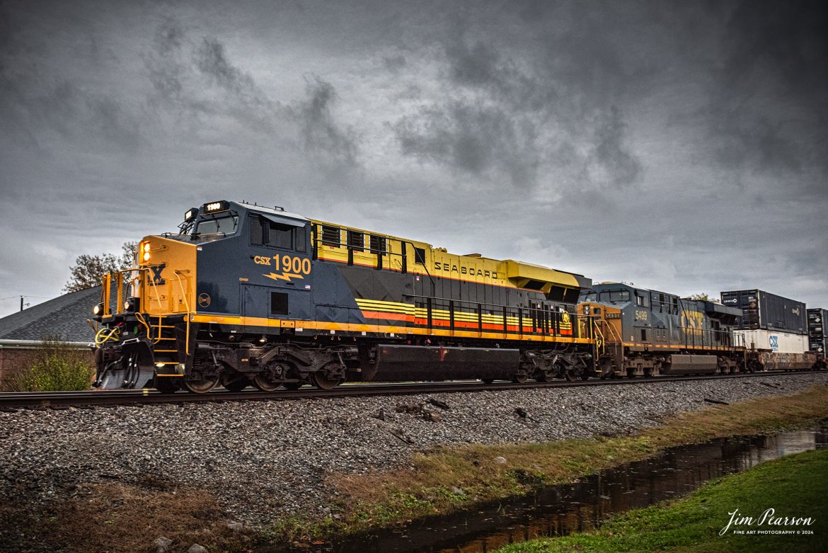 CSX I026 with CSX Seaboard Air Line Railroad Heritage Unit, 1900 leading, heads north at Crofton, Kentucky on the CSX Henderson Subdivision, on November 13th, 2024, under stormy skies. 

According to a CSX Press Release: August 29, 2024 - CSX has unveiled its 18th heritage locomotive, a tribute to the Seaboard Air Line Railroad, marking another milestone in celebrating the rich history of American railroads. This latest addition to CSX's heritage series honors the legacy and the significant role that the Seaboard Air Line Railroad played in shaping the rail transport landscape in the United States.

The Seaboard Air Line Railroad, originally established in the late 19th century, was renowned for its efficient service and innovative routes, connecting the southeastern United States to the broader nation. Over the decades, it became famous for its passenger and freight services, symbolized by its slogan "Through the Heart of the South."

In 1967, Seaboard Air Line merged with the Atlantic Coast Line Railroad to form the Seaboard Coast Line Railroad. This merger was part of a larger trend in the railroad industry aimed at increasing efficiency and competitiveness. Eventually, Seaboard Coast Line became part of CSX Corporation in the 1980s through a series of mergers and consolidations that included the Chessie System and other lines. This ultimately positioned CSX as one of the leading rail networks in the U.S.

The creation of the Seaboard Air Line heritage unit was no small feat, showcasing the meticulous craftsmanship and dedication of ONE CSX team. Jeromy Hutchison, a CSX carman painter, commented on the complexity of the project, stating, "This was one of our harder projects. All of the stripes on the unit are hand laid, making it very complicated." The intricate detailing is a testament to the commitment delivering a great work product and honoring the legacy of the railroad. 

Tech Info: Nikon D810, RAW, Nikon 24-70 @ 24mm f/2.8, 1/400, ISO 2200.

#besttrainphotograph #bestphoto #photographyoftrains #bestsoldpicture #JimPearsonPhotography #csxheritagelocomotive #onecsx