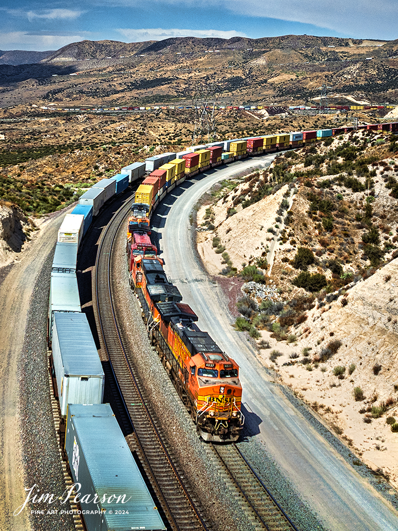 September 20th, 2024, Two BNSF pass each other at the at the Summit of Cajon Pass in southern California and the BNSF Cajon Subdivision.

According to Wikipedia: Cajon Pass is a mountain pass between the San Bernardino Mountains to the east and the San Gabriel Mountains to the west in Southern California. Created by the movements of the San Andreas Fault, it has an elevation of 3,777 ft (1,151 m). Located in the Mojave Desert, the pass is an important link from the Greater San Bernardino Area to the Victor Valley, and northeast to Las Vegas. The Cajon Pass area is on the Pacific Crest Trail.

Cajon Pass is at the head of Horsethief Canyon, traversed by California State Route 138 (SR 138) and railroad tracks owned by BNSF Railway and Union Pacific Railroad. Improvements in 1972 reduced the railroad's maximum elevation from about 3,829 to 3,777 feet while reducing curvature. Interstate 15 does not traverse Cajon Pass, but rather the nearby Cajon Summit. The entire area, Cajon Pass and Cajon Summit, is often referred to as Cajon Pass, but a distinction is made between Cajon Pass and Cajon Summit.

The California Southern Railroad, a subsidiary of the Atchison, Topeka and Santa Fe Railway, was the first railroad through Cajon Pass. The line through the pass was built in the early 1880s to connect the present-day cities of Barstow and San Diego. Today the Union Pacific Railroad and BNSF Railway (the successor to the Santa Fe) use the pass to reach Los Angeles and San Bernardino as part of the Southern Transcon. Due to the many trains, scenery and easy access, it is a popular location for railfans, and many photographs of trains on Cajon Pass appear in books and magazines.

Tech Info: DJI Mavic 3 Classic Drone, RAW, 24mm, f/2.8, 1/3200, ISO 100.

#railroad #railroads #train, #trains #railway #railway #steamtrains #railtransport #railroadengines #picturesoftrains #picturesofrailways #besttrainphotograph #bestphoto #photographyoftrains #bestsoldpicture #JimPearsonPhotography #trainsfromtheair #trainsfromadrone #CajonPass

#railroad #railroads #train, #trains #railway #railway #steamtrains #railtransport #railroadengines #picturesoftrains #picturesofrailways #besttrainphotograph #bestphoto #photographyoftrains #bestsoldpicture #JimPearsonPhotography #trainsfromtheair #trainsfromadrone #CajonPass