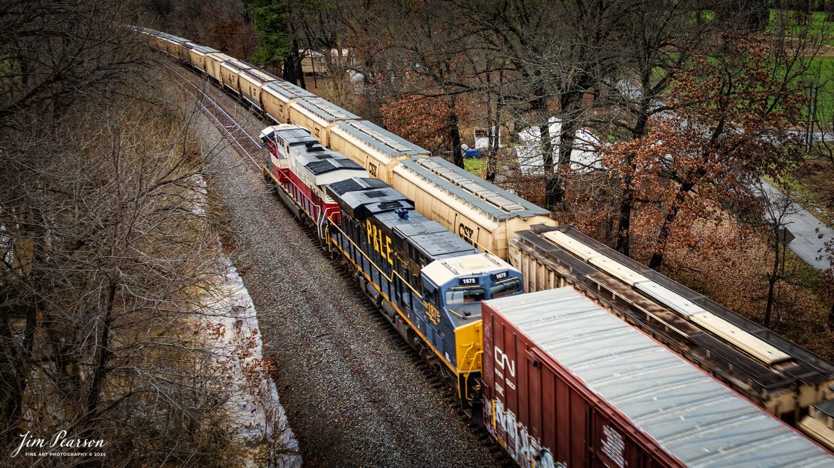 This is my first catch where there were two CSX Heritage Units leading a train! I got word about this move on CSX M648 the day before and when it finally arrived where I setup to catch it the first time at Mortons Gap, Ky the wind and rain was bad, but I did get a short video clip here is in my December 21st, 2024, Saturday Edited Video.

In this shot the Western Maryland and P&LE Heritage units leading M648 they pass G387 at Robards, Kentucky, on the CSX Henderson Subdivision on December 16th 2024.

According to the CSX Website: The Western Maryland Railroad operated between 1852 and 1983 in Maryland, West Virginia, and Pennsylvania. It was a small railroad that primarily transported coal and freight.

“In 1983 the Western Maryland fully merged with the B&O (Baltimore and Ohio Railroad), which merged with the C&O (Chesapeake and Ohio Railroad) in 1987. They eventually merged with the Seaboard System to form CSX.” explained Tim Music, a CSX carman painter who assisted with the project.

The Pittsburgh & Lake Erie Railroad was established in 1875 with a primary mission of transporting essential industrial materials such as coal, coke, iron ore, limestone, and steel among the bustling industrial hubs of the region.

“It’s mainline connected Pittsburgh, Pennsylvania with Youngstown, Ohio and Connellsville, Pennsylvania. It did not actually reach Lake Erie until 1976,” explained Tim Music, a carman painter at the CSX Waycross Locomotive Shop where the unit was produced.

Despite its relatively modest route mileage, the P&LE Railroad earned the nickname “Little Giant” due to the enormous volume of heavy tonnage it moved. This impressive capability drew significant attention and by 1887, the P&LE became a subsidiary of the dominant New York Central Railroad. Under this new ownership, the P&LE enjoyed substantial improvements to its tracks and added capacity for passenger services, further enhancing its regional significance.

Tech Info: DJI Mavic 3 Classic Drone, RAW, 24mm, f/2.8, 1/80, ISO 120.

#railroad #railroads #train, #trains #railway #railway #railtransport #railroadengines #picturesoftrains #picturesofrailways #besttrainphotograph #bestphoto #photographyoftrains #bestsoldpicture #JimPearsonPhotography #trainsfromadrone #csxheritagelocomotives