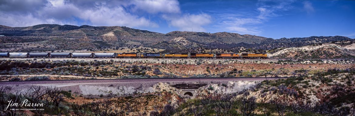 Film Wednesday – Union Pacific 9491 leads a lash-up of six locomotives as they strain to pull their mixed freight up the famous Cajon Pass in southern California, in this film scan from a 6x17cm slide that was shot sometime in the early 1990’s. 

According to Wikipedia: The Atchison, Topeka and Santa Fe Railway (reporting mark ATSF), often referred to as the Santa Fe or AT&SF, was one of the largest Class 1 railroads in the United States between 1859 and 1996.

The Santa Fe was a pioneer in intermodal freight transport; at various times, it operated an airline, the short-lived Santa Fe Skyway, and the Santa Fe Railroad tugboats. Its bus line extended passenger transportation to areas not accessible by rail, and ferryboats on the San Francisco Bay allowed travelers to complete their westward journeys to the Pacific Ocean. The AT&SF was the subject of a popular song, Harry Warren and Johnny Mercer's "On the Atchison, Topeka and the Santa Fe", written for the film The Harvey Girls (1946).

The railroad officially ceased independent operations on December 31, 1996, when it merged with the Burlington Northern Railroad to form the Burlington Northern and Santa Fe Railway.

Tech Info: Camera, Fuji 6x17, Kodachrome Slide Film, no other data recorded, Scanned with an Epson Perfection V700 PHOTO scanner.

#slidescan #filmphotography #trains #railroads #jimpearsonphotography