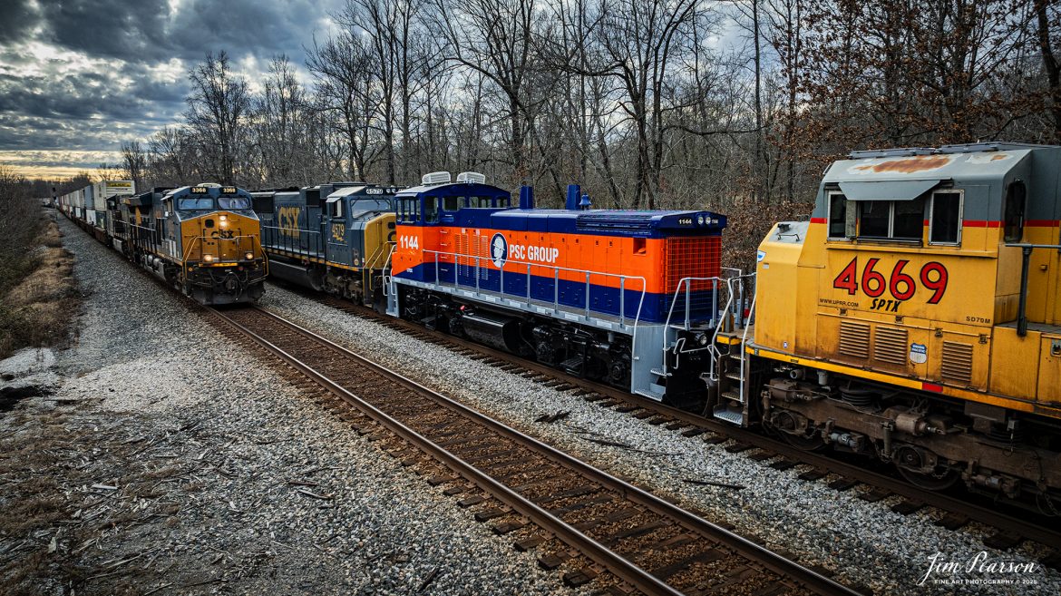 Southbound CSX M513 waits at Romney, south of Nortonville, Kentucky as CSX northbound Intermodal I128 passes them on track 2, on January 17th, 2025, on the Henderson Subdivision.

M513 has PCS Group Switcher 1144 as the third unit and an ex-Union Pacific 4669 with reporting marks of SPTX stenciled on the side of the cab, with both units dead in tow.

According to their website, “PSC Group provides turnkey solutions for safe and efficient rail switching in some of the most challenging and complex sites throughout North America. We manage more than 75 rail switching sites using our own fleet of advanced locomotives and mobile railcar movers, proven safety methods, and highly skilled personnel. By working closely with our customers, we tailor our services to their unique needs, utilizing over 80 locomotives, 30 mobile railcar movers (Trackmobiles and Shuttle Wagons), and more than 1,000 skilled employees to enhance safety, decrease cycle time, prevent derailments, and optimize railcar utilization.

Over the years, we have found that performing railcar switching alongside loading/unloading, railcar repair, and inspections, creates a safer and more efficient operating environment while simultaneously delivering considerable savings. By bundling these synergistic services together, we can provide the most value to our customers' operations.”

However, I can’t find much information on the SPTX Reporting mark so if anyone can provide me with some, I’d appreciate it!

Tech Info: DJI Mavic 3 Classic Drone, RAW, 24mm, f/2.8, 1/1250, ISO 270.

#bestphoto #trains #bestsoldpicture #JimPearsonPhotography #trainsfromtheair #trainsfromadrone