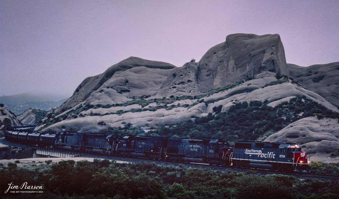 Film Wednesday – Southern Pacific 9768 leads a tank train as it heads through the Mormon Rocks area in the Cajon Pass in southern California, in this film scan from a Kodachrome slide that was shot sometime in the early 1990’s. 

According to Wikipedia: The Southern Pacific (reporting mark SP) (or Espee from the railroad initials) was an American Class I railroad network that existed from 1865 to 1996 and operated largely in the Western United States. The system was operated by various companies under the names Southern Pacific Railroad, Southern Pacific Company and Southern Pacific Transportation Company.

The original Southern Pacific began in 1865 as a land holding company. The last incarnation of the Southern Pacific, the Southern Pacific Transportation Company, was founded in 1969 and assumed control of the Southern Pacific system. The Southern Pacific Transportation Company was acquired in 1996 by the Union Pacific Corporation and merged with their Union Pacific Railroad.

Tech Info: Camera, Nikon F3, Kodachrome Slide Film, no other data recorded

#slidescan #filmphotography #trains #railroads #jimpearsonphotography