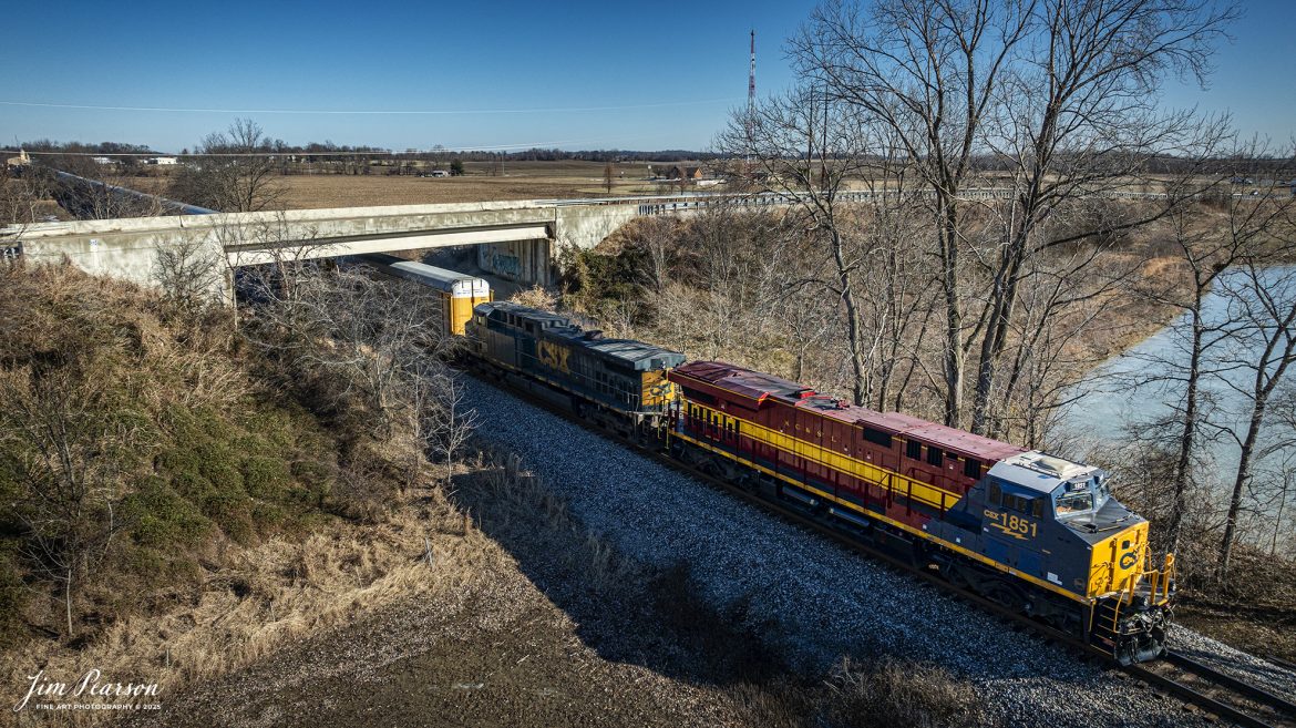 CSX I025 with CSX NC&SL Heritage Unit 1851 leading, heads south under the Henderson By-Pass at Henderson, Kentucky on the CSX Henderson Subdivision, on January 27th, 2025. 

According to a CSX Press Release: September 20, 2024 - Railroads have long played a crucial role in shaping the economic and cultural landscapes of the United States. Among these storied lines is the Nashville, Chattanooga, and St. Louis (NC&StL) Railway, a key player in the growth of the Southeast. CSX has unveiled its 19th heritage locomotive, a tribute to the NC&StL Railway, celebrating the rich legacy of a system integral to regional development.

Operating from 1851 to 1957, the NC&StL Railway was a vital freight and passenger route, connecting communities across Tennessee and other Southern states. It facilitated the movement of goods and people, boosting commerce and fostering community development along its routes. The railway's strategic links between Nashville, Chattanooga, and St. Louis significantly contributed to the urban and industrial growth of these cities, supporting industries such as agriculture, coal, and manufacturing.

To honor the historical significance of the NC&StL Railway, CSX introduced the Nashville, Chattanooga, and St. Louis heritage locomotive. This initiative is part of CSX’s broader program to preserve the legacy of railroads that are now part of its extensive network. Each heritage unit is carefully crafted to pay homage to the unique identity and history of its predecessor, featuring colors and designs reminiscent of the original rail lines. 

Tech Info: DJI Mavic 3 Classic Drone, RAW, 22mm, f/2.8, 1/2000, ISO 160.

#besttrainphotograph #bestphoto #photographyoftrains #bestsoldpicture #JimPearsonPhotography #csxheritagelocomotive #onecsx