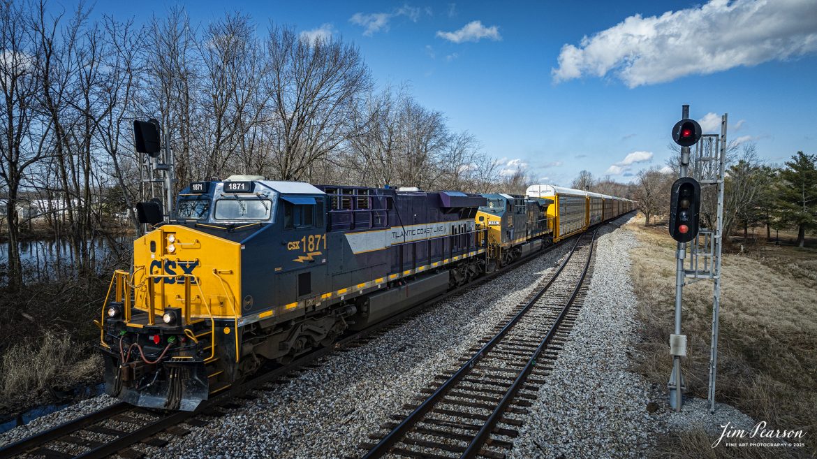 Atlantic Coast Line Heritage Unit CSXT 1871 passes the signals at the north end of Crofton, Ky, on January 31st, 2025, as it leads hot intermodal I025 southbound on the CSX Henderson Subdivision. The autoracks behind the power are hauling Tesla's bound for Florida.

According to a CSX Press Release: November 29, 2023 – The CSX fleet of heritage locomotives is continuing to grow with the introduction of a unit painted in a custom design honoring the Atlantic Coast Line Railroad.

Designated CSX 1871, the seventh locomotive in the heritage series was unveiled at the CSX Locomotive Shop in Waycross, Georgia, which has designed and applied the paint schemes for all the heritage units. The latest in the series features the modern CSX design on the head end, transitioning to historic paint scheme and logo of the Atlantic Coast Line at the rear.

The Atlantic Coast Line name first appeared in 1871, and the American Coast Line Railroad (ACL) was officially incorporated in 1900. The ACL extended from Georgia to Richmond, Virginia, and later expanded into Florida. In 1960, the company opened a new headquarters building in Jacksonville, which continues as CSX headquarters to this day. The ACL merged with the Seaboard Air Line Railroad in 1967 to form the Seaboard Coast Line, which later became part of CSX.

“We do a lot of research on the colors and the schemes just to make sure that we get it right,” said Jeromy Hutchison, CSX carman painter. “We want to make sure we do our heritage justice.”

CSX 1871 will carry the ACL colors in service across the 20,000-mile CSX network, reinforcing employee pride in the history of the railroad that continues to move the nation’s economy with safe, reliable and sustainable rail-based transportation services.

Tech Info: DJI Mavic 3 Classic Drone, RAW, 22mm, f/2.8, 1/2000, ISO 160.

#trainphotography #railroadphotography #trains #railways #jimpearsonphotography #onecsx #csxheritageunits