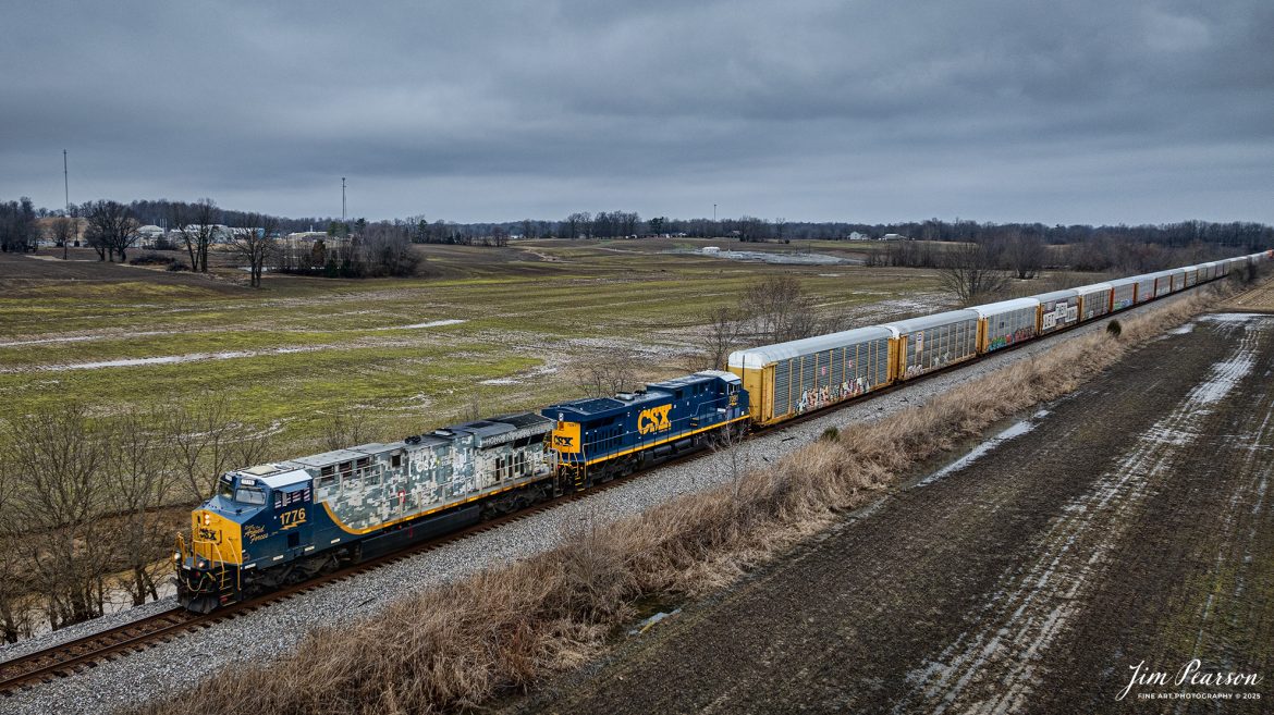 CSX hot intermodal 025, with the 1776 specialty locomotive leading, heads south, just north of Slaughters, Ky, on the CSX Henderson Subdivision on February 6th, 2025. All the autoracks behind the power are carrying Tesla’s bound for southern Florida.

According to a press release from CSXT, ES44AH locomotive No. 1776, dubbed “The Spirit of Our Armed Forces,” was unveiled 0n April 30, 2019, at the railroad’s Huntington Heavy Repair shops in West Virginia.

No. 1776, renumbered from No. 3112, wears a combination standard CSX scheme on its cab and a highly detailed digital camouflage paint scheme on its long hood which adorns CSX’s new “Pride in Service” logo. The seals of the five-armed services branches are spread across the rear of the engine’s radiators, and logos for several support organizations for veterans and veterans’ families also appear on the locomotive. A screen-printed American flag covers the side cab windows.

Tech Info: DJI Mavic 3 Classic Drone, RAW, 24mm, f/2.8, 1/1000, ISO 150.

#railroad #railroads #train, #trains #railway #railway #railtransport #railroadengines #picturesoftrains #picturesofrailways #besttrainphotograph #bestphoto #photographyoftrains #bestsoldpicture #JimPearsonPhotography #trainsfromadrone