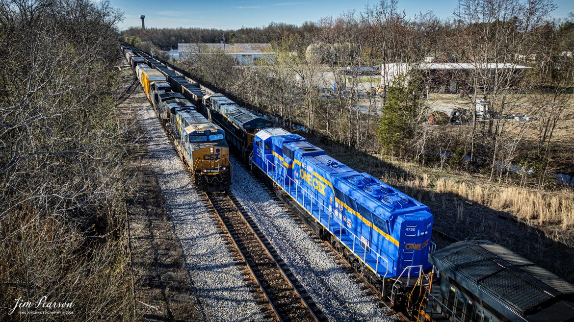 CSX M647 heads southbound as it passes combined coal (E040) and ethanol train (B622) with the We Are One CSX locomotive 4720 as a mid-train DPU at Guthrie, Kentucky on March 18th, 2025, on the CSX Henderson Subdivision. This is my first time catching this locomotive out in the wild and while I wish it had been leading but I’ll take what I can get!  I totally love the look of this locomotive!

According to a CSX press release, January 14, 2025 - CSX has introduced the ONE CSX locomotive, a specially designed engine to symbolize the company’s commitment to fostering collaboration, inclusion, and mutual respect across its workforce.

“This locomotive celebrates our ONE CSX team and culture,” said CSX President and Chief Executive Officer Joe Hinrichs. “I am so proud to work with 23,000 members of our ONE CSX team every day to keep America moving.”

The locomotive’s vibrant design was created by Jody Cremeans, a Carman Painter at CSX’s mechanical shop in Huntington, West Virginia. Cremeans’ design reflects the company’s cultural pillars of valuing, appreciating, including, and respecting every individual within its organization. Employees at CSX’s Waycross, Georgia, mechanical shop brought the design to life, meticulously painting and polishing the locomotive to perfection.

Prominently displayed on the locomotive are the logos of 14 labor unions that represent CSX employees, reinforcing the company’s commitment to collaboration. This special detail of the locomotive further exemplifies CSX’s focus on working together to deliver exceptional customer service while ensuring every employee feels valued and connected.

“The ONE CSX cultural initiative has been a great way for management and craft employees to come together, to work together and to value each other,” explained Jon Guest, Assistant Superintendent at the CSX Waycross Terminal.

The ONE CSX locomotive serves as a rolling tribute to the importance of teamwork and mutual respect within the organization. For CSX, its success is directly tied to creating a workplace that fosters unity and celebrates each employee’s contributions.

The new locomotive stands as a testament to the power of shared purpose within the organization and represents CSX’s aspiration to continue building an inclusive and respectful workplace.

Tech Info: DJI Mavic 3 Classic Drone, RAW, 22mm, f/2.8, 1/1250, ISO 150.

#railroad #railroads #train, #trains #railway #railway #railtransport #railroadengines #picturesoftrains #picturesofrailways #besttrainphotograph #bestphoto #photographyoftrains #bestsoldpicture #JimPearsonPhotography #trainsfromadrone #csxhendersonsubdivision #onecsx