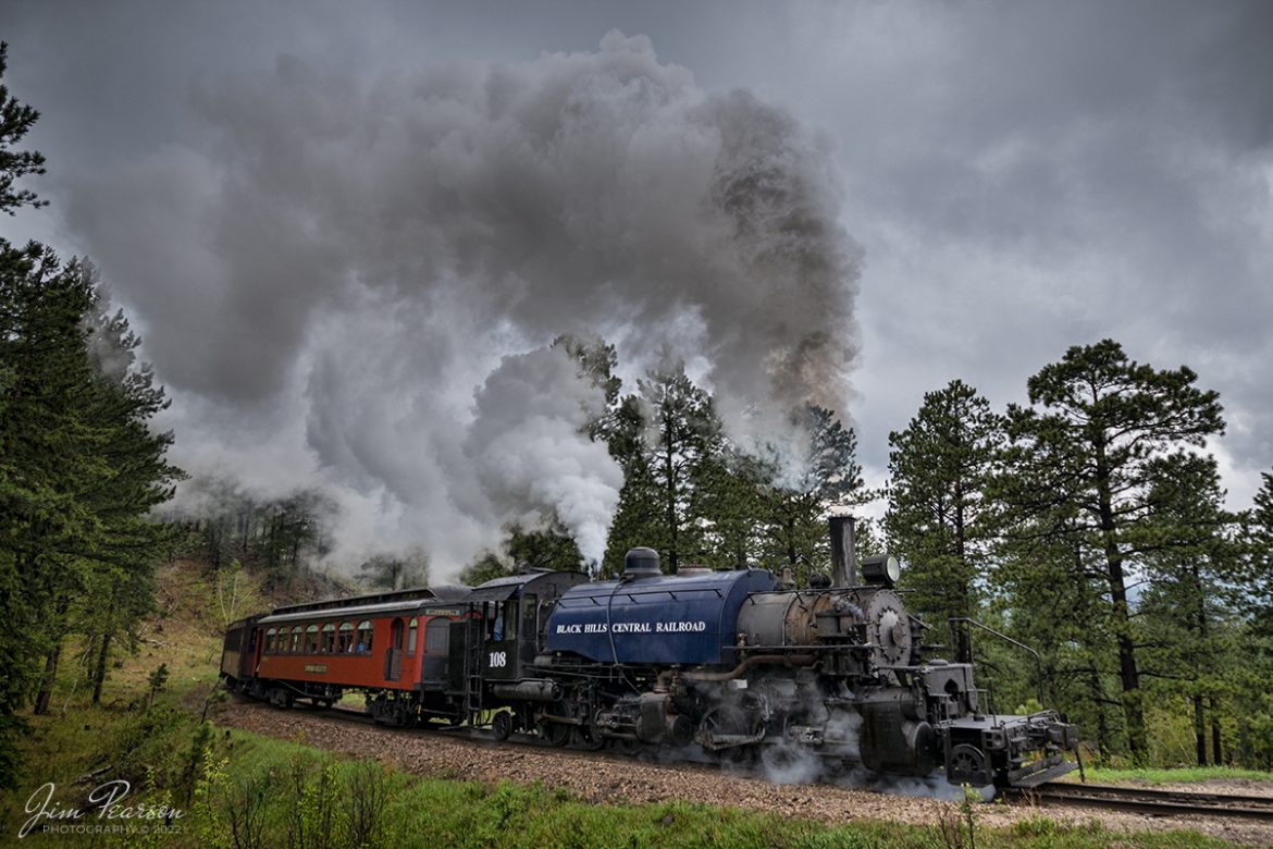 The Black Hills Central Railway locomotive 108 heads through the countryside as it makes its first trip of the day in stormy, wet weather of the forest to Keystone, South Dakota on my birthday, May 30th, 2022! I for one cant recall a better way to spend the day then chasing a steam locomotive and they later in the day riding it with family! Despite the wet and rainy weather, it was a great day, and I even got the drone up a few times! A big shout out to Cory Jakeway for all the help on finding my way around on the railroad and railfanning with me! 

According to their website: Locomotive #108 joined its nearly identical twin, #110, at the beginning of the 2020 season following a four-year restoration. It is a 2-6-6-2T articulated tank engine that was built by the Baldwin Locomotives Works in 1926 for the Potlatch Lumber Company. It later made its way to Weyerhaeuser Timber Company and eventually to the Northwest Railway Museum in Snoqualmie, Washington.

The acquisition and subsequent restoration of locomotive #108 completed a more than 20-year goal of increasing passenger capacity which began with the restoration of #110 and the restoration of multiple passenger cars. Both large Mallet locomotives (pronounced Malley) can pull a full train of seven authentically restored passenger cars, up from the four cars utilized prior to their addition to the roster.

Tech Info: Nikon D800, RAW, Nikon 10-24mm @ 13mm, f/3.8, 1/400, ISO 250.

#trainphotography #railroadphotography #trains #railways #jimpearsonphotography #trainphotographer #railroadphotographer