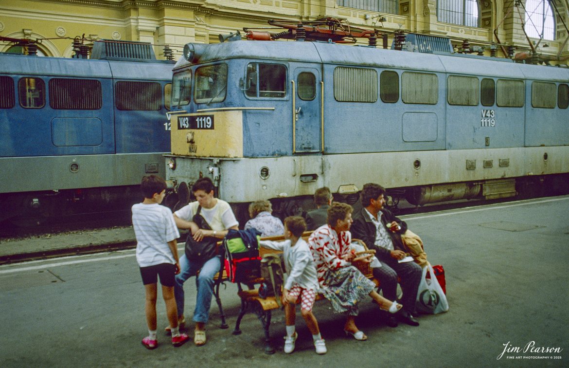 Film Wednesday – 1993 – Today’s slide scans are from time that I spent at the Budapest-Nyugati Railway Station, in Budapest, Hungry. In this shot families wait on the platform for their train to arrive.

According to Wikipedia, Budapest Nyugati station (Hungarian: Nyugati pályaudvar, pronounced [ˈɲuɡɒti ˈpaːjɒudvɒr]; lit. 'western railway station'), generally referred to simply as Nyugati, is one of the three main railway terminals in Budapest, Hungary. The station is on the Pest side of Budapest, accessible by the 4 and 6 tramline and the M3 metro line.

The station was designed by Auguste de Serres and was built by the Eiffel Company. It was opened on 28 October 1877. It replaced another station, which was the terminus of Hungary's first railway line, the Pest–Vác line (constructed in 1846). This building was demolished to construct the Grand Boulevard.

The station got its name from the adjacent Western Square ('Nyugati tér'), a major intersection where Teréz körút (Theresia Boulevard), Szent István körút (Saint Stephen Boulevard), Váci út (Váci Avenue), and Bajcsy-Zsilinszky út (Bajcsy-Zsilinszky Avenue) converge. The square also serves as a transport hub with several bus routes, tram routes 4 and 6, and a station on M3 of the Budapest Metro.

Beside the terminal and partially above its open area there is the WestEnd City Center shopping mall. Inside the station is a McDonald's restaurant which has been described as the "most elegant" McDonald's in the world.

The music video for Gwen Stefani's 2008 single Early Winter was partly shot at Nyugati. Starting in May 2016 the key scenes of the movie Terminal were shot over 27 nights.

Tech Info: Camera, Nikon F3, Ektachrome Slide Film, no other data recorded, Scanned with an PlusTek 82001i Film Scanner.

#slidescan #filmphotography #trains #railroads #jimpearsonphotography #FilmPhotography